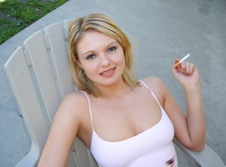 Cute blond girl smokes a cigarette before unleashing her natural tits in jeans